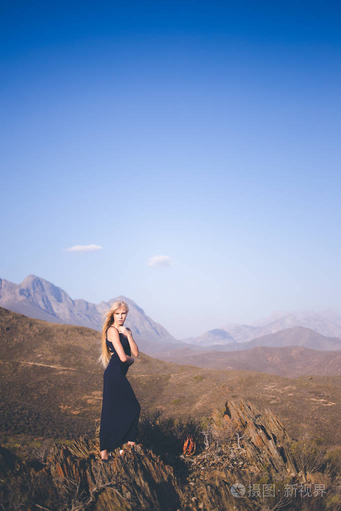 美丽的金发女郎站在山上欣赏风景