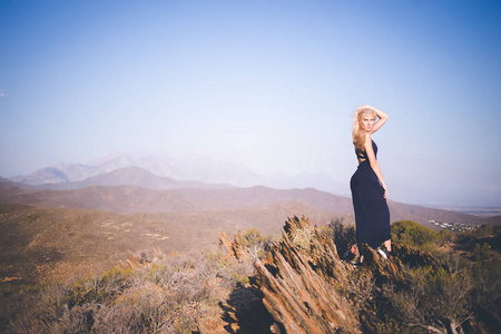 美丽的金发女郎站在山上欣赏风景