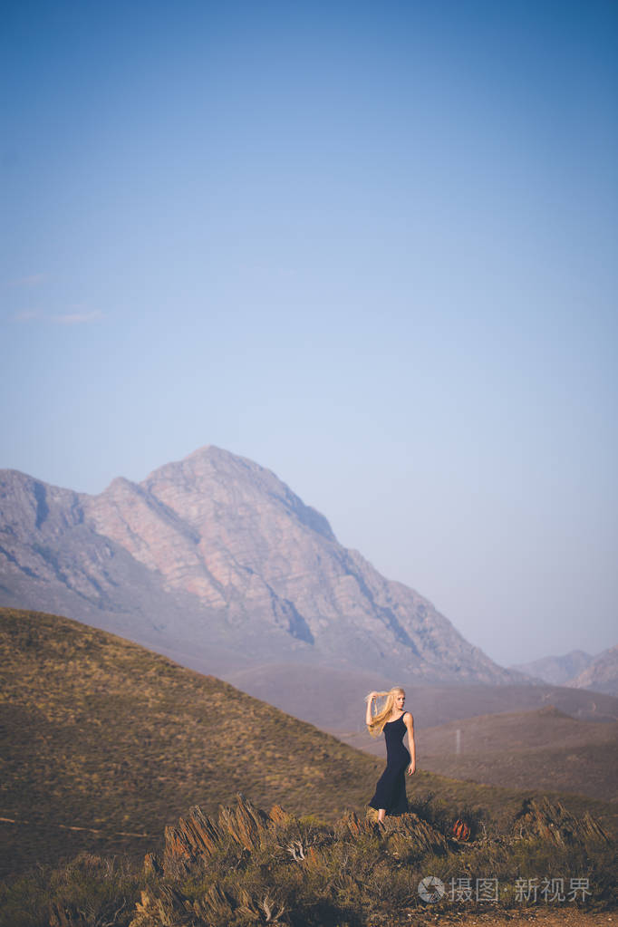 美丽的金发女郎站在山上欣赏风景