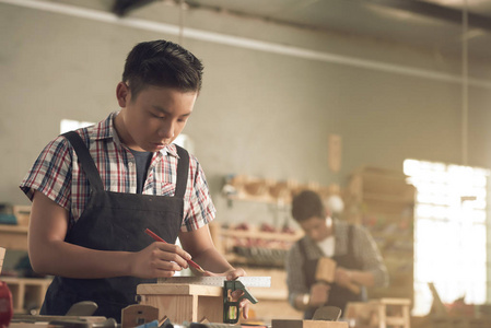 男孩用尺子测量亚洲少年木匠用尺子量木板照片