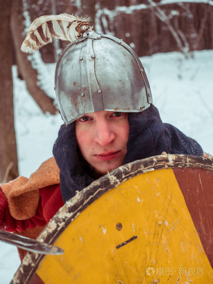 法兰克战士在历史服装用剑, 盾, 盔甲在冬天森林里