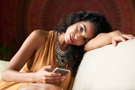 无聊的年轻女子在沙发上放松时给朋友发短信