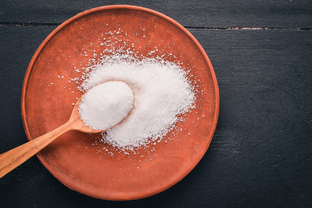 在盘子上用木勺放盐.在木制背景上.上景.免费的文本空间.照片