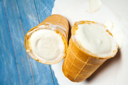 华夫饼杯里的冰淇淋勺。 白色木头和蓝色背景的华夫饼里的冰淇淋。 华夫饼碗中美味的冰淇淋
