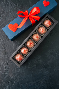 蓝色的礼物盒与红色带巧克力的黑色石头背面