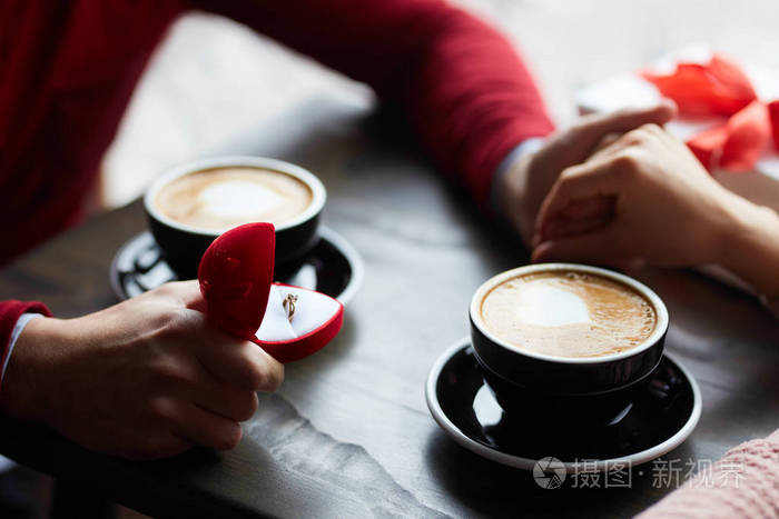 恋爱中的夫妇牵着手在咖啡馆里喝咖啡和分享礼物. 男人在求婚.
