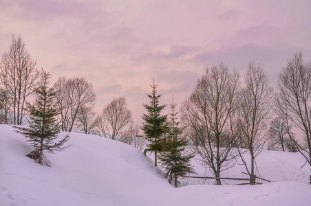 冬夜。 白雪覆盖的山上有一片温柔的粉红色天空。