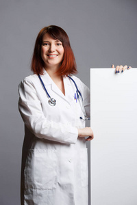 女性医生的图片白色外套和与 phonendoscope 点手指在空白纸片