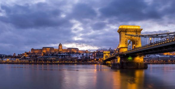 布达佩斯, 匈牙利美丽的照亮塞切尼链桥梁在多瑙河与布达城堡皇家宫殿在蓝色小时