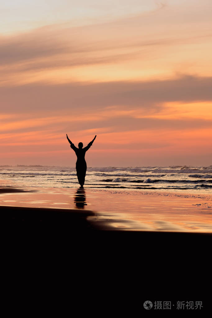 日落时分一个女人在海面上举起双手