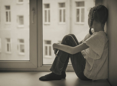 看看忧郁问题可怜的小女孩坐在窗边.黑白照片