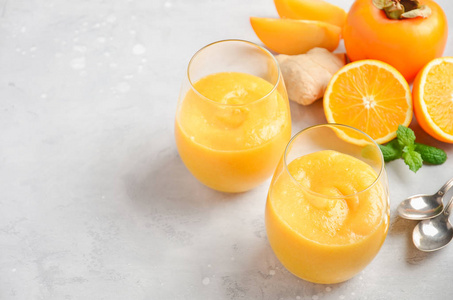 新鲜的健康冰沙，用柿子橘子和生姜在灰色混凝土背景上。选择性聚焦，复制空间..