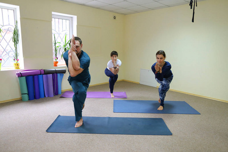 年轻女子瑜伽教练教男孩和女孩做 exer