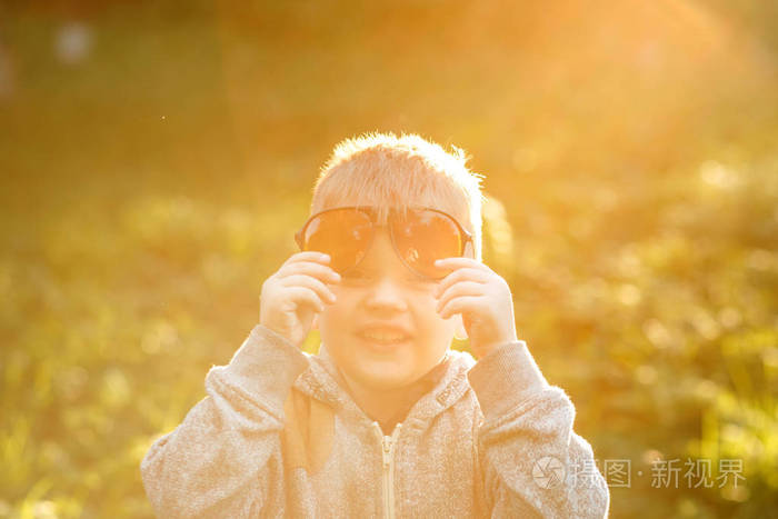 夏天花园里戴黄色太阳镜的滑稽小男孩