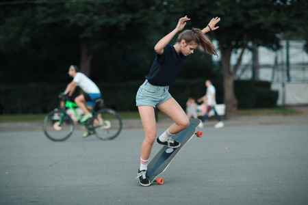 在公园里骑着长板的年轻运动女子