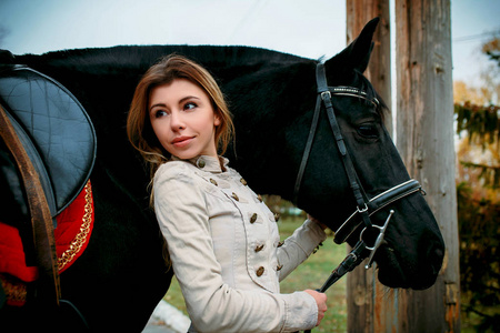 一个多梦的金发女人，带着一匹马靠近木栅栏