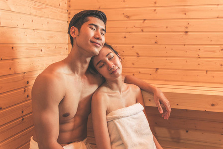 年轻的亚洲情侣或情侣在桑拿房里享受浪漫的放松。皮肤护理热处理和身体清洁和刷新在温泉与蒸汽浴。健康和蜜月的概念。幸福在一起