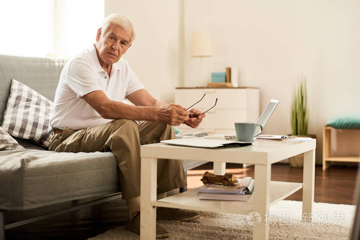 疲惫的老人在家工作的肖像,沉思着