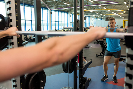 肌肉发达的人准备在健身房举起沉重的杠铃，看镜子反射