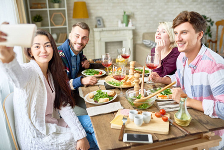 快乐的朋友在庆祝节日时坐在餐桌上自拍的照片照片