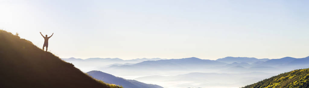 山顶上的人。 情感场景。 带背包的年轻人站在山顶上，欣赏山景。 山顶上的徒步旅行者。 运动和积极的生活理念。