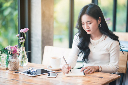 亚洲青年女性在咖啡馆写笔记