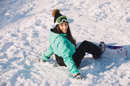 微笑的女孩滑雪坐在雪地上