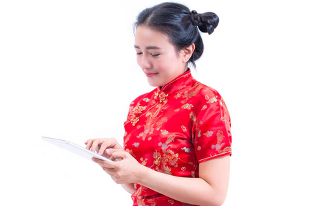 美丽的年轻的亚洲妇女的侧面图的肖像穿着中国传统旗袍或旗袍使用现代数字平板电脑, 概念购买数字在线, 技术, 孤立的白色背景