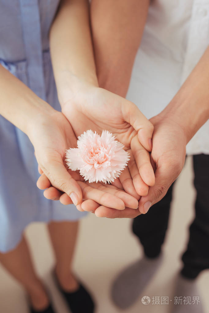 恋爱中的一对双手握着粉红色的花