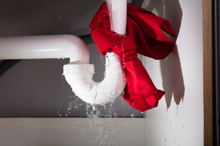 把红色餐巾纸绑在漏水的白色水槽管下面
