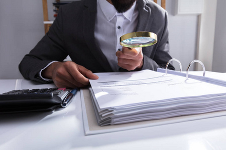 s Hand Analyzing Bill With Magnifying Glass At Workplace