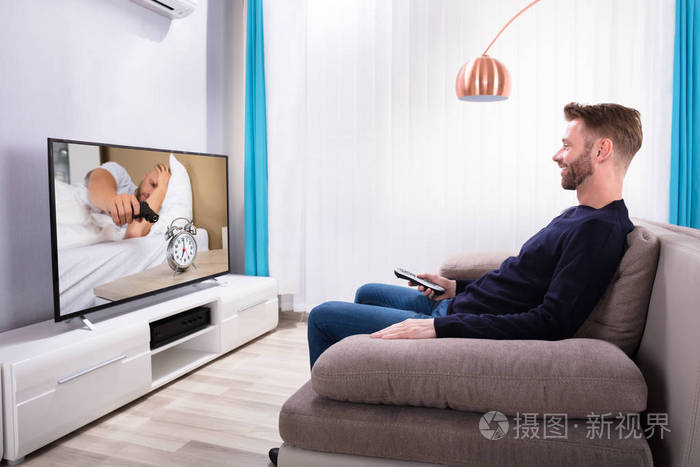 坐在沙发上看电视的快乐年轻人
