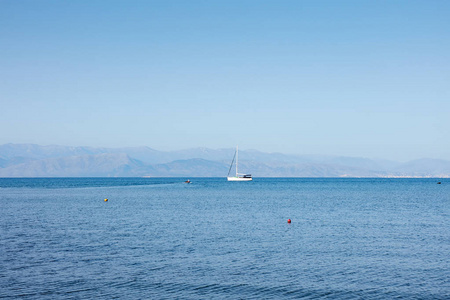 奇妙的海滨景色，在海上单独的游艇在地平线科孚岛希腊。 晴天极简主义平静而沉默。
