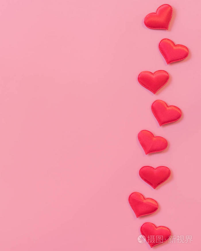 红色的心脏在粉红色柔和的颜色背景与空间为文本