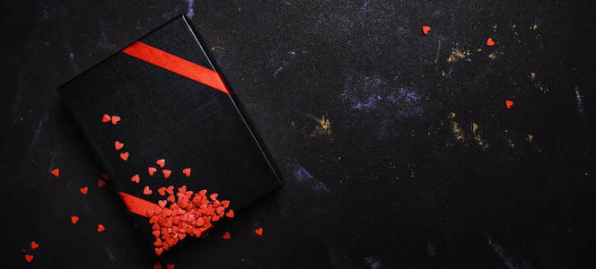情人节礼物送给男人，黑盒子，红色丝带，甜蜜的心，黑暗的背景，顶部的景色
