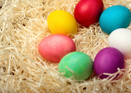 五颜六色的复活节彩蛋在圆圈中排列。与 羽毛。白色羽毛色的鸡蛋。在干草背景。复活节背景。顶部视图