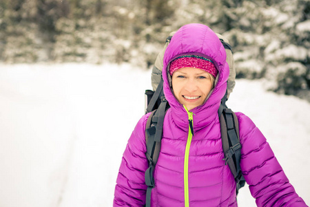 女人带着背包在白色的冬天森林里徒步旅行。走在雪地小径上的年轻女孩。休闲健身和健康生活方式，户外露营。动机和励志冬季景观..