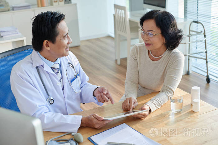 医生手拿数码平板电脑向亚洲病人展示化验结果