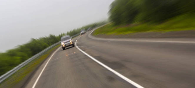 汽车骑在贯穿森林的乡村道路上