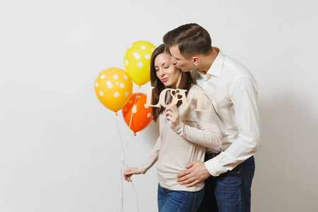 爱的情侣接吻。男人, 女人用木字的爱, 黄色的, 橙色的气球在白色背景上隔离。广告。St. 情人节, 国际妇女节, 生日假期概念
