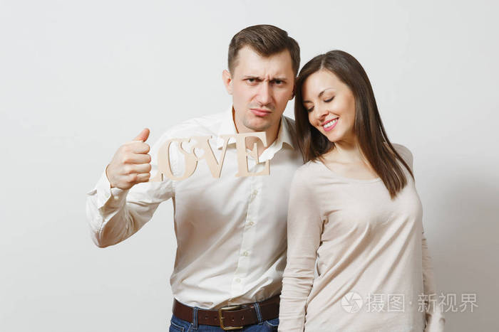热恋中的情侣严重的男人, 甜美的女人用木字的爱孤立在白色的背景.