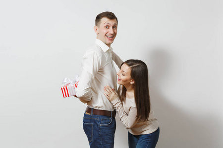 可爱有趣的情侣在爱。女人背后的男人谁躲在他身后的红色礼品盒在白色背景的礼物隔离。St. 情人节, 国际妇女节的生日假期概念