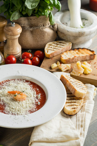 意大利奶油汤，奶酪番茄面包和罗勒，放在木制的灰色厨房桌子上