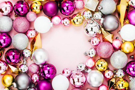 粉红色背景上闪亮的圣诞球和金色水晶的俯视图