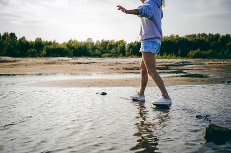 可爱的卷发少女浪漫的青春漫步在温暖的夏日阳光明媚的沙滩上与水共渡