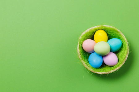 六彩色粉彩声道画复活节彩蛋篮子与绿草隔离在绿色背景。复活节快乐的概念。广告的复制空间。与地方为文本。顶部查看鸡蛋