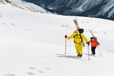 两个滑雪 freerider 爬上斜坡到深雪粉与设备上的背部固定在背包