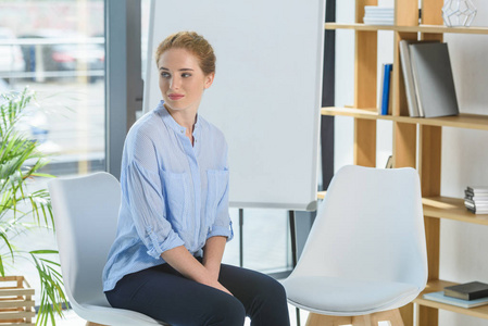 年轻的女商人坐在现代办公室的椅子上