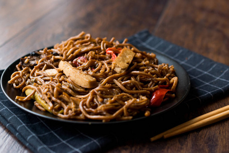 黑盘子里有豆腐和红辣椒的素食面条