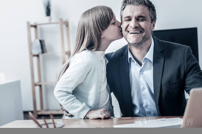 迷人的女儿亲吻她的爸爸脸颊